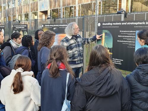 Pupils talk to scientist in front of exhibition panel